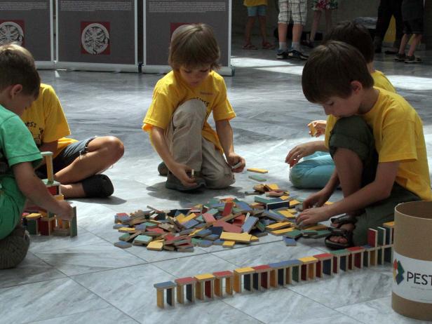 Mehrere Kinder sitzen auf dem Boden und spielen mit bunten Holzbausteinen.
