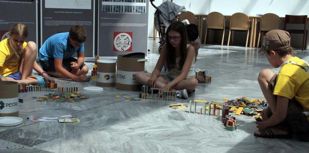 Kinder sitzen auf dem Boden und spielen mit Dominosteinen.