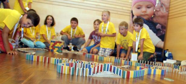 Eine Gruppe Kinder baut eine lange Domino-Kette auf dem Boden.