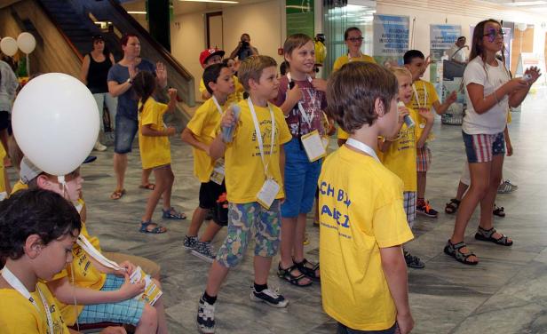 Eine Gruppe Kinder in gelben T-Shirts mit Ballons in einem Gebäude.