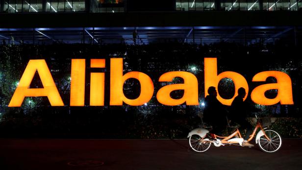FILE PHOTO: People ride double bicycle past Alibab