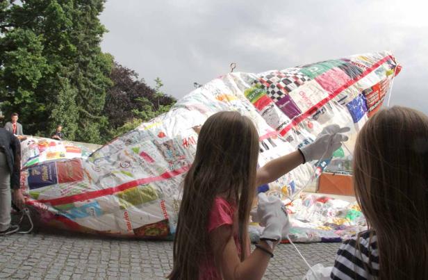 Zwei Mädchen hantieren mit einem großen, bunten, patchworkartigen Ballon.