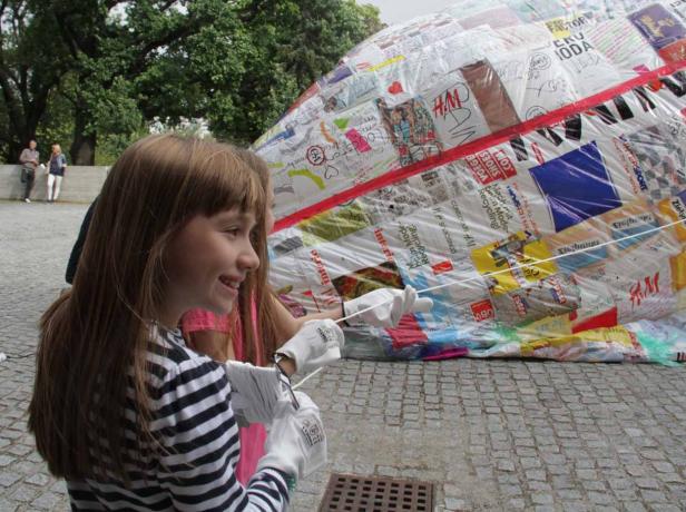 Ein Mädchen hält die Schnüre eines großen, mit Logos beklebten Objekts.