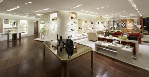 Innenansicht eines luxuriösen Schuhgeschäfts mit Auslagen und Sitzgelegenheiten.