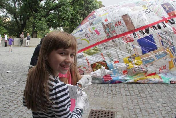 Ein Mädchen steht vor einem großen, mit Logos und Zeichnungen bedeckten Objekt.