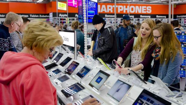 Kunden betrachten Tablets und Smartphones in einem Elektronikgeschäft.