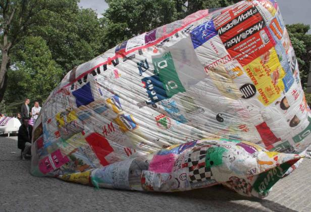 Eine große, mit Logos und Schriftzügen beklebte Skulptur im Freien.