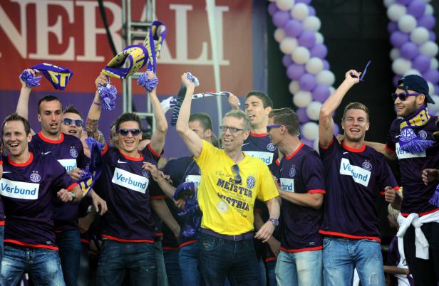 Eine Gruppe von Fußballspielern feiert mit Fans auf einer Bühne.