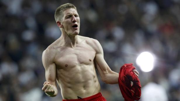 Ein jubelnder, barfüßiger Bastian Schweinsteiger hält sein Trikot in der Hand.