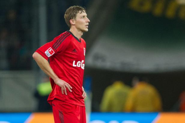 Ein Fußballspieler in roter Spielkleidung mit den Händen an den Hüften.