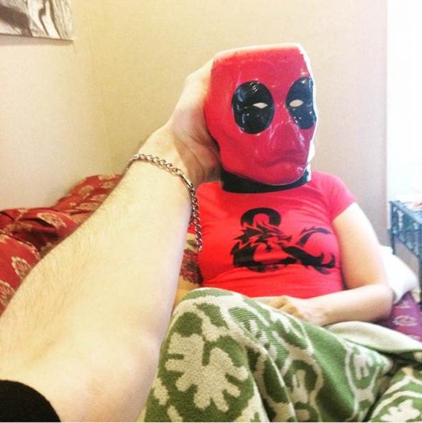 Eine Person mit einer Deadpool-Maske und einem Dungeons & Dragons-T-Shirt sitzt auf einem Sofa.