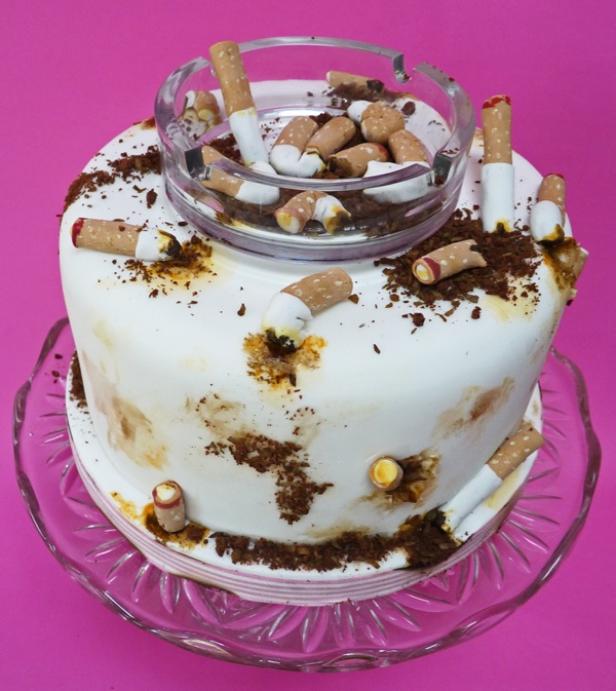Ein Kuchen, der mit Zigarettenstummeln und einem Aschenbecher dekoriert ist.