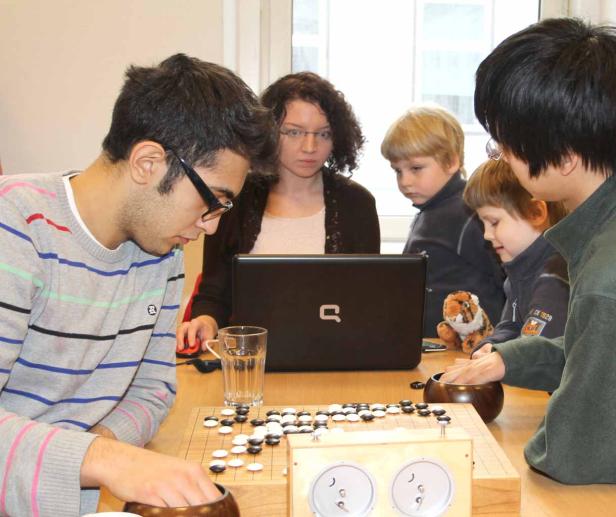 Eine Gruppe von Menschen spielt das Brettspiel Go an einem Tisch.