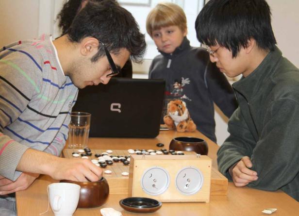 Zwei Männer spielen Go, während ein Kind zusieht.