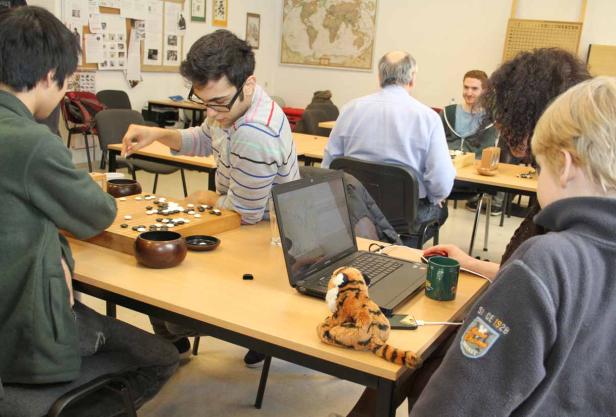 Mehrere Personen spielen Go an Tischen in einem Raum.