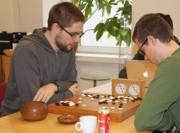 Zwei Männer spielen das Brettspiel Go an einem Tisch.