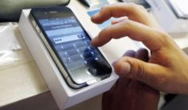 Eine Person tippt auf dem Bildschirm eines Smartphones, das in seiner Verpackung liegt.
