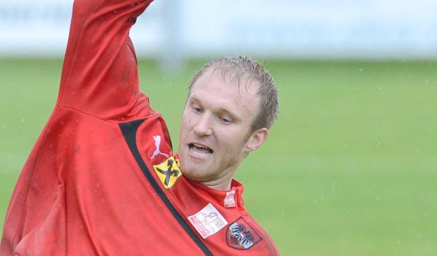 Ein österreichischer Fußballspieler in roter Trainingskleidung während eines Spiels.