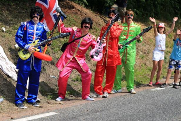 Eine Gruppe von als die Beatles verkleideten Personen posiert mit Spielzeuggitarren und einer Union Flagge.