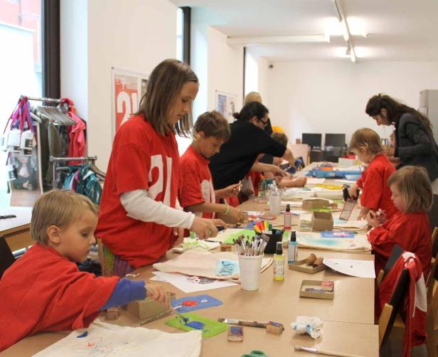 Eine Gruppe Kinder bastelt an einem langen Tisch in einem hellen Raum.