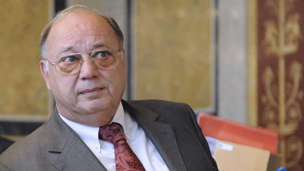 Ein Mann mit Brille und Anzug blickt zur Seite.