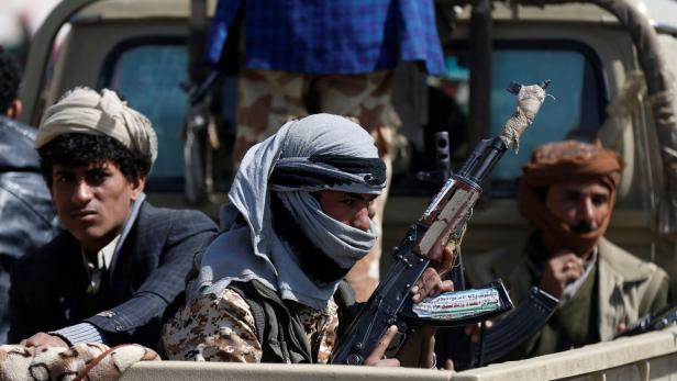 Houthi fighters ride on the back of a truck as cla