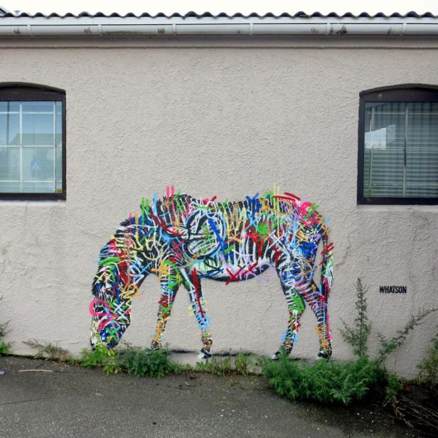 Ein Graffiti eines grasenden Zebras an einer Hauswand.
