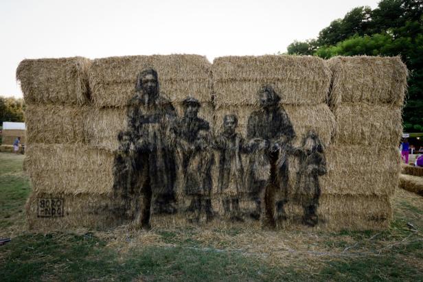 Ein Kunstwerk auf einem Strohballenstapel zeigt eine Familienszene.