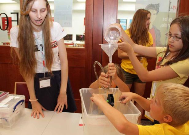 Eine Gruppe Kinder führt ein Experiment mit Wasser und einem Trichter durch.
