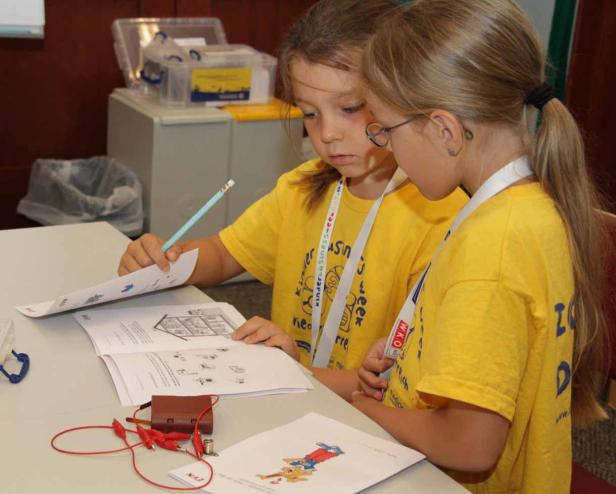 Zwei Mädchen in gelben T-Shirts arbeiten an einem Projekt mit Schaltkreisen.