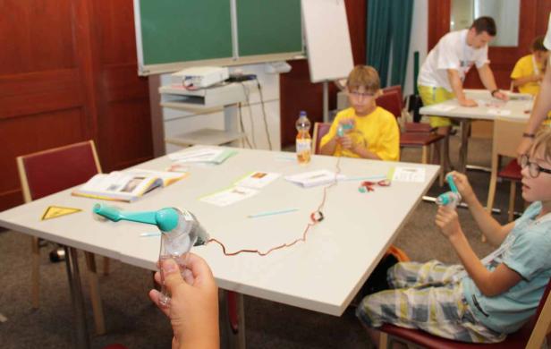 Kinder experimentieren mit kleinen Elektromotoren in einem Klassenzimmer.