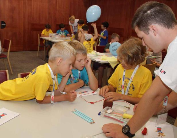 Kinder experimentieren mit einem Stromkreis unter Aufsicht eines Erwachsenen.