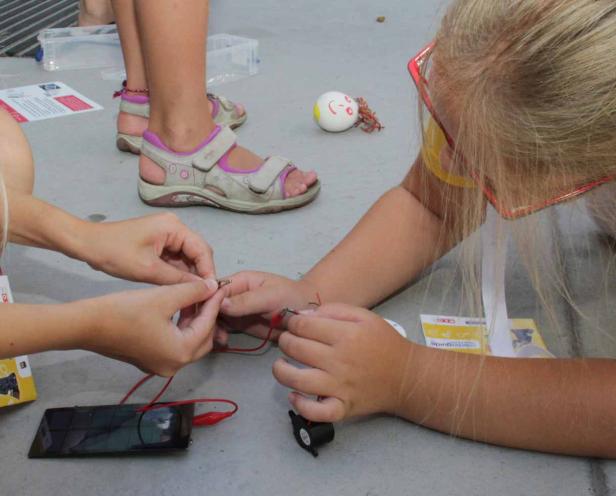Kinder experimentieren mit einem Solarmodul und elektrischen Bauteilen.