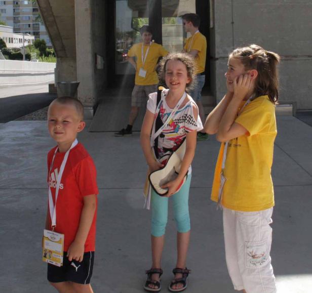 Eine Gruppe Kinder steht vor einem Gebäude, einige tragen gelbe T-Shirts.