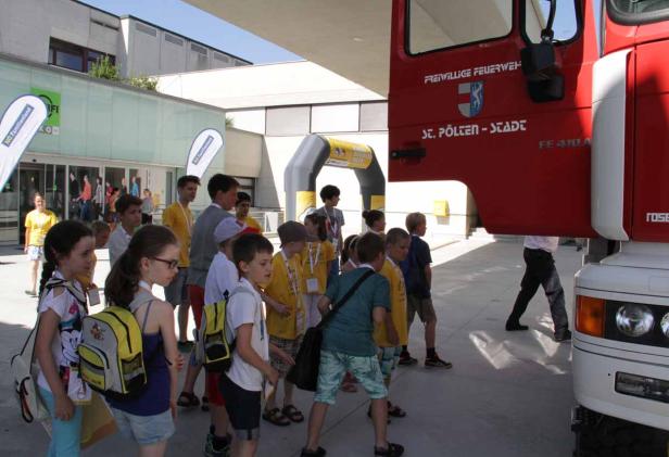 Eine Gruppe Kinder steht vor einem roten Feuerwehrauto der Freiwilligen Feuerwehr St. Pölten.
