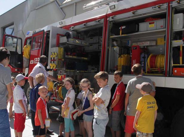 Eine Gruppe Kinder steht vor einem geöffneten Feuerwehrwagen.