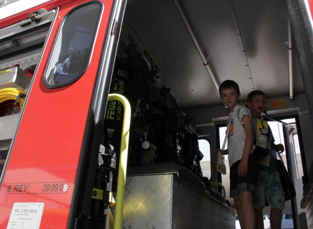 Zwei Jungen stehen im Inneren eines roten Feuerwehrautos.