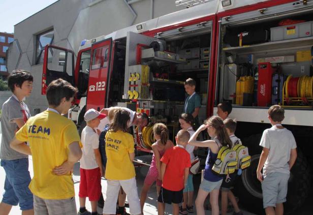 Eine Gruppe Kinder steht vor einem geöffneten Feuerwehrwagen.