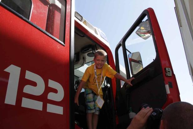 Ein Junge steigt in ein rotes Feuerwehrauto mit der Nummer 112.