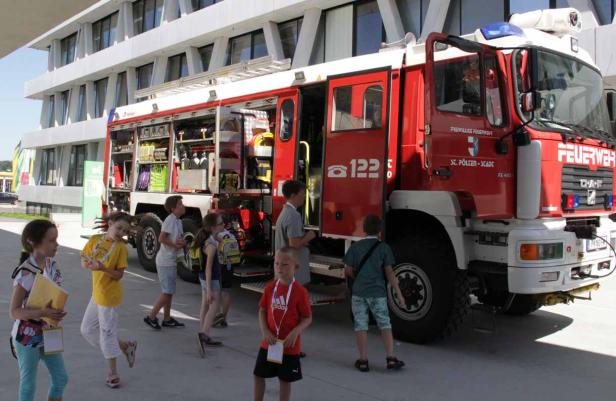 Eine Gruppe Kinder steht vor einem roten Feuerwehrauto der Freiwilligen Feuerwehr St. Pölten-Stadt.