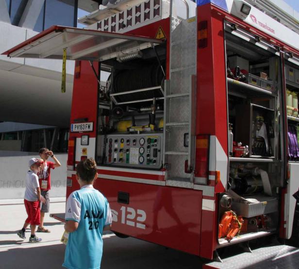 Ein offenes Feuerwehrfahrzeug mit Kindern im Hintergrund.