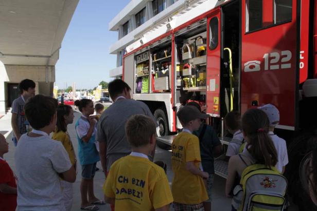 Eine Gruppe Kinder steht vor einem geöffneten Feuerwehrwagen.