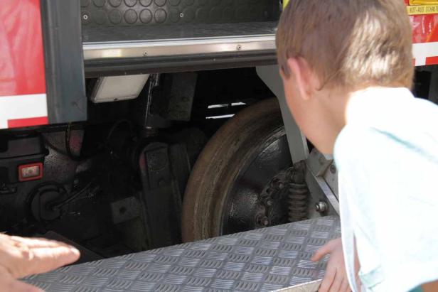 Ein Junge betrachtet das Rad eines großen Fahrzeugs.