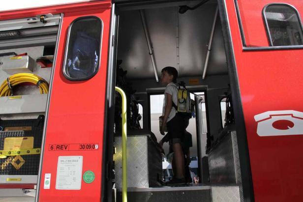 Ein Junge steht in der offenen Tür eines roten Schienenfahrzeugs.