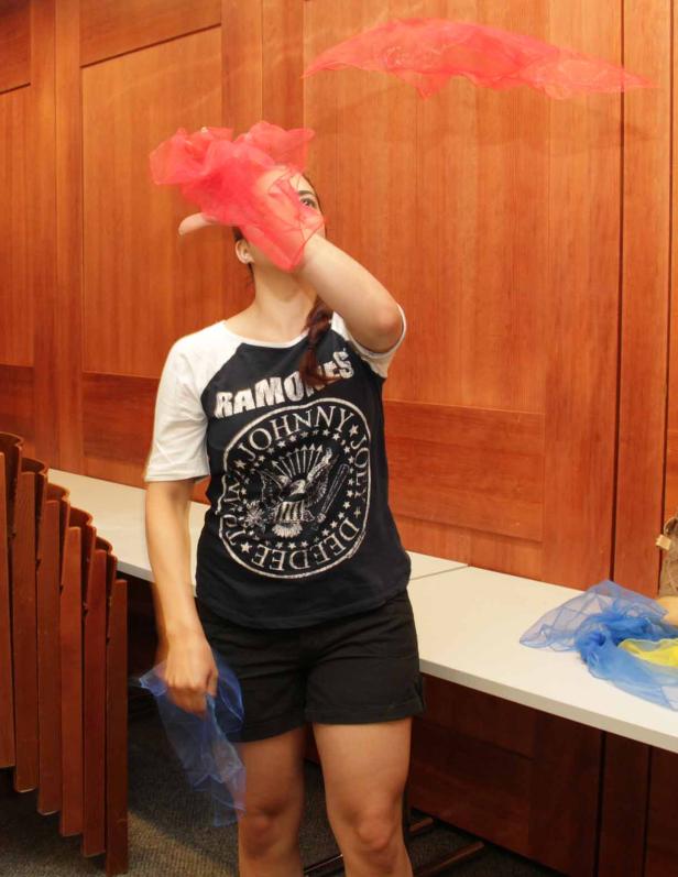 Eine Frau mit einem Ramones-T-Shirt wirft rote Tücher in die Luft.