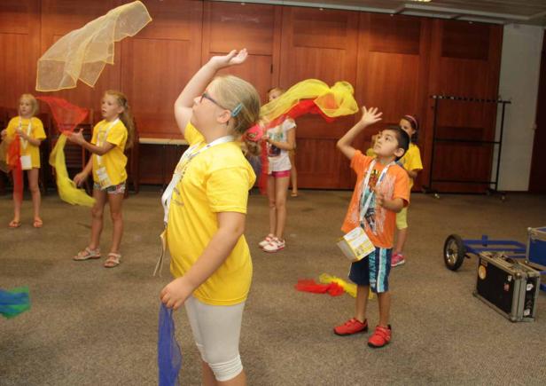 Eine Gruppe Kinder spielt mit bunten Tüchern in einem Raum.