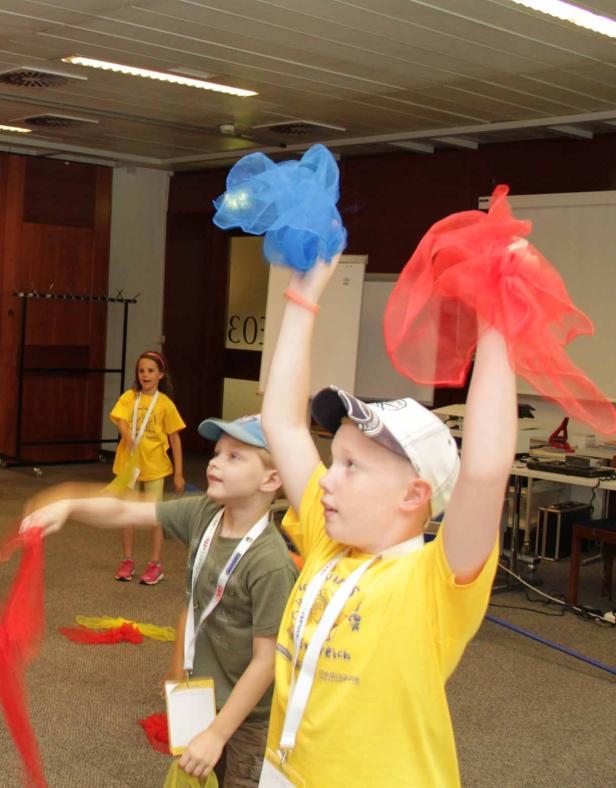 Kinder spielen mit bunten Tüchern in einem Raum.
