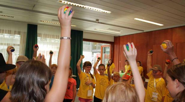 Eine Gruppe Kinder hält bunte Bälle in die Luft.