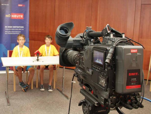 Zwei Jungen sitzen vor einer Kamera des ORF und werden interviewt.