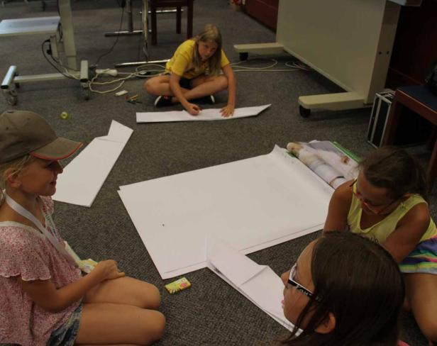 Eine Gruppe Mädchen sitzt auf dem Boden und bastelt mit Papier.